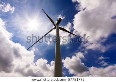 Wind turbine over a cloud filled blue sky, alternative energy source