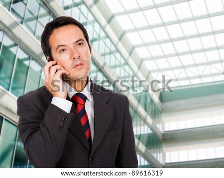 A handsome business man talking on the phone at his office building