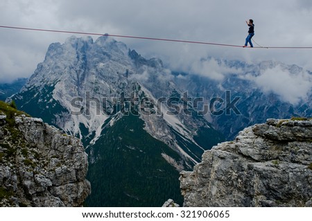 MONTE PIANA, DOLOMITES/ITALY - SEPTEMBER 08, 2013: an acrobat on a rope tended above an abyss during \