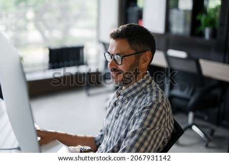 Close Up Young Man in Fashion Glasses Eye Looking Monitor, Surfing Internet. Stylish Male Working With computer From Home in Him Home Office. The Monitor Screen Is Reflected In The Glases
 Foto stock © 