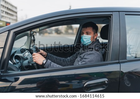 a man driving a car puts on a medical mask during an epidemic, a taxi driver in a mask, protection from the virus. Driver in black car. coronavirus, disease, infection, quarantine, covid-19 商業照片 © 