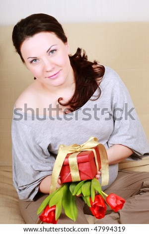 Beautiful pregnant woman with a gift and a bouquet of tulips