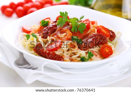 Spaghetti with tomato sauce, sun dried tomato and shrimps on white plate