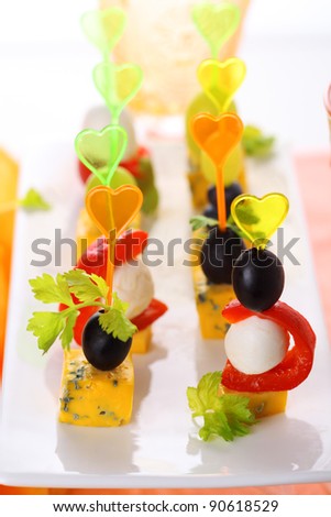 Canape platter with cheese, roasted peppers, olives and grapes.