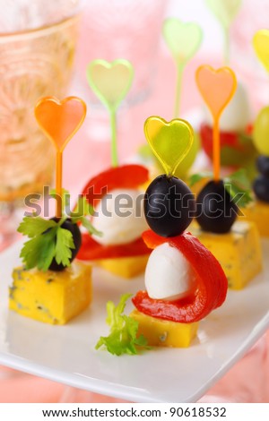 Canape platter with cheese, roasted peppers, olives and grapes close up.