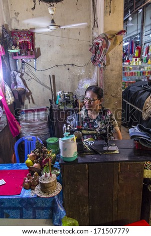 SIEM REAP, CAMBODIA- SEPT 21: The market traders in the local food markets in Siem Reap, Cambodia, September 21st  2013, Siem Reap, Cambodia, A seamstress plys her trade in the bustling market place