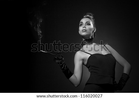 Beautiful girl  portrait in retro style. Glamorous woman in black outfit holding a cigarette