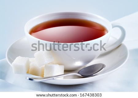Black tea with sugar cubes in white cup. Macro