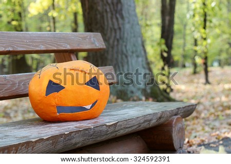 Pumpkin papier-mache mask laying on a wooden bench in the autumn park