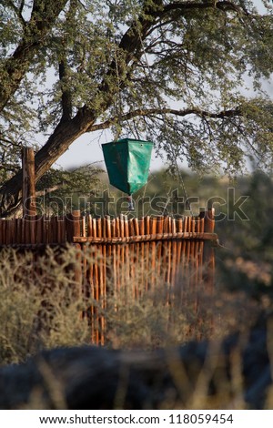 A plastic bucket shower hanging under a tree in a safari camp in africa