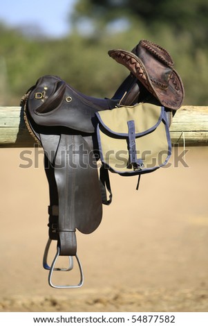 A vertical photograph of horse riding tack, including saddle, bag and leather hat