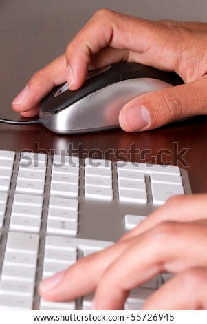 A close up of a man typing and working with mouse