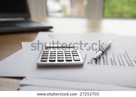 Pen, laptop & calculator on finance documents.  Logos, numbers, signature etc have been removed or changed to make unidentifiable.