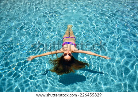 Female beauty relaxing in swimming pool, top view