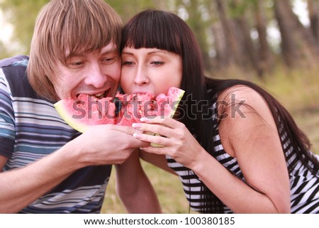 Young couple eating water melon. Pair with a watermelon  couple on a picnic in the forest together bite a one piece of watermelon - a symbol of unity and oneness