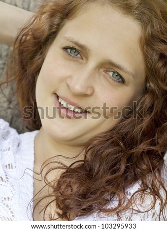 young blue-eyed smiling woman in white against blurred forest background with selective focus and copy space