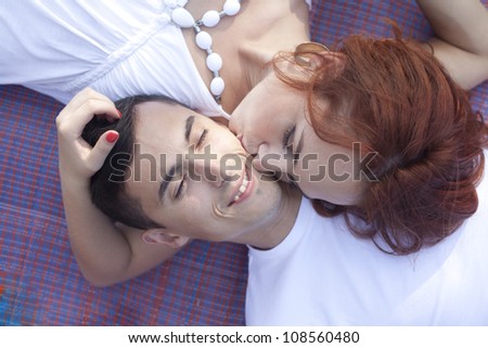 20 years old man and woman relaxing and lying down in a meadow