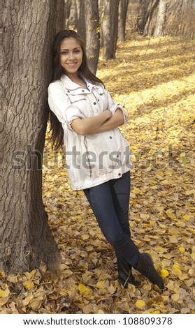 Young slim latin woman in autumn forest in full growth