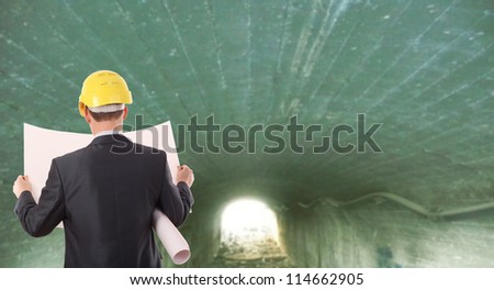 Rear view worker in a tunnel light at end of tunnel