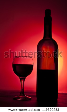 Elegant red wine glass and a wine bottle in black and red gradient background