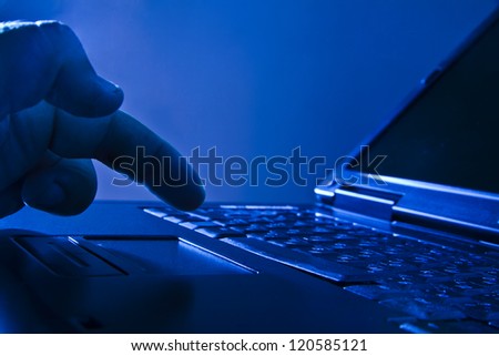 Silhouetted image someone typing on laptop computer Symbol shadow economy illegal operations cracking computer passwords fraud hacking advertising sales illegal non payment taxes concealment income