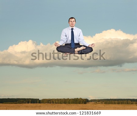 Businessman meditating sitting on the white cloud over  field of wheat