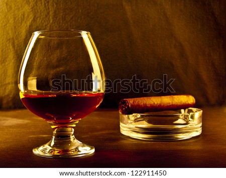 bottle and glass of brandy and cigar on black background