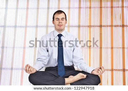 Businessman at the office in lotus yoga position on the backgrou