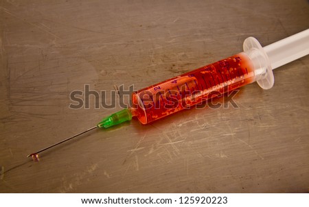 syringes with red liquid isolated over yellow metal  background.