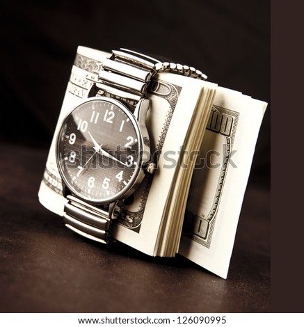 Rolled bundle of one hundred dollars notes inside locked belt of modern wristwatch Time is money