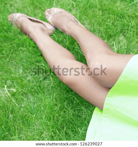 slender legs young girl on green grass