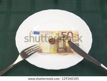 money lying on a plate wit a fork and a knife beneath