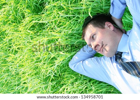 Over head close up portrait of a successful businessman laying down on green grass
