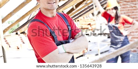 working couple - woman and man - two Young builders on a background of metal roof trusses