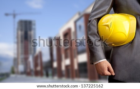 engineer yellow helmet for workers security on the background of a new high-rise apartment buildings and construction cranes and blue cloudy sky