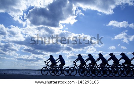 Image of sporty company friends on bicycles outdoors against sunset. Silhouette A lot phases of motion of a single cyclist along the shoreline coast