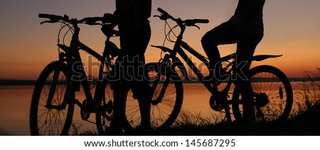 silhouettes of couples in love ride bicycles along the beach No faces