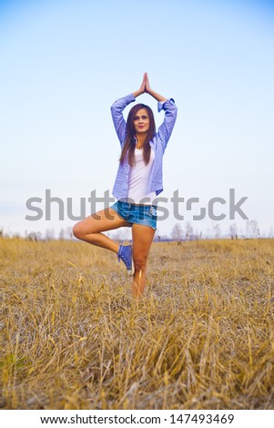 girl practicing yoga in yellow wheat field Copy space for inscription