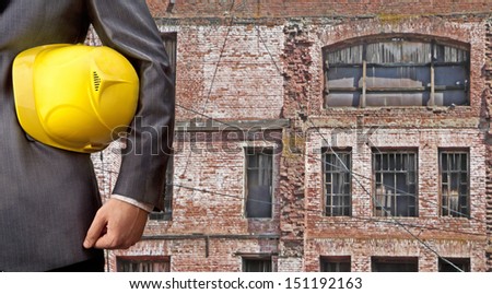 engineer yellow helmet for workers security against the backdrop of the restored old red brick building with windows and wooden frames  Copy Space for inscription