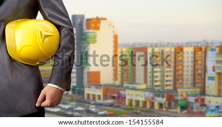 engineer yellow helmet for workers security on the background of a new high-rise apartment buildings evening sunset sky Copy space for inscription