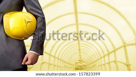 worker or engineer holding in hands yellow helmet for workers security on the background of a new concrete bridge over the river in perspective buildings gray idea  building new road junctions