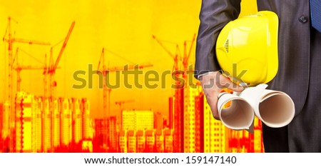 engineer yellow helmet for workers security on the background of a new high-rise apartment buildings and construction cranes and evening sunset sky