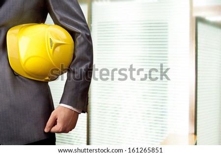 engineer yellow helmet for workers security over glass office window with shutters background