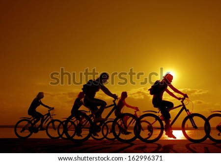 3 romantic couples cyclists ride towards each other silhouette in sunrise against sun set cloudy sky and sea shore background Space for inscription
