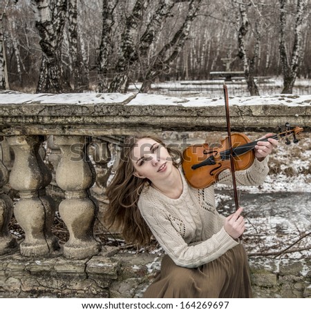 Young sexy with long hair with a broken violin on old retro fence and  stairway in the Gothic style of classicism