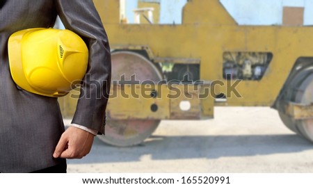 engineer yellow helmet for workers security against the background of the metal roller asphalt spreader