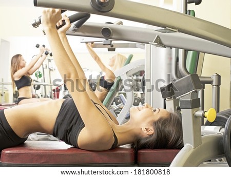 Portrait of three young adult Girls do exercise for legs and hands. in fitness gym on mirror with reflection and window background 3 woman with long blond and brunette hair sitting smiling face