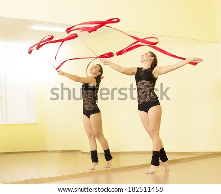 Portrait of cut Pretty rhytmic gymnast girl exercising with red ribbon with reflection on mirror yellow wall background Caucasian Woman in sexy lace transparent suit and woolen golfs stand on one leg