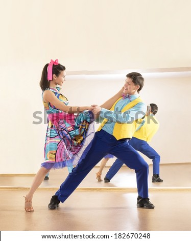 Portrait of two Happy teenage retro dance band on in very colorful dress on mirror reflection on wall background Two man and one woman full length looking at camera