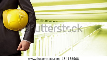 torso worker or engineer hand holding in hands yellow helmet for workers security on background of a new concrete bridge over the river in perspective buildings gray idea building new road junctions